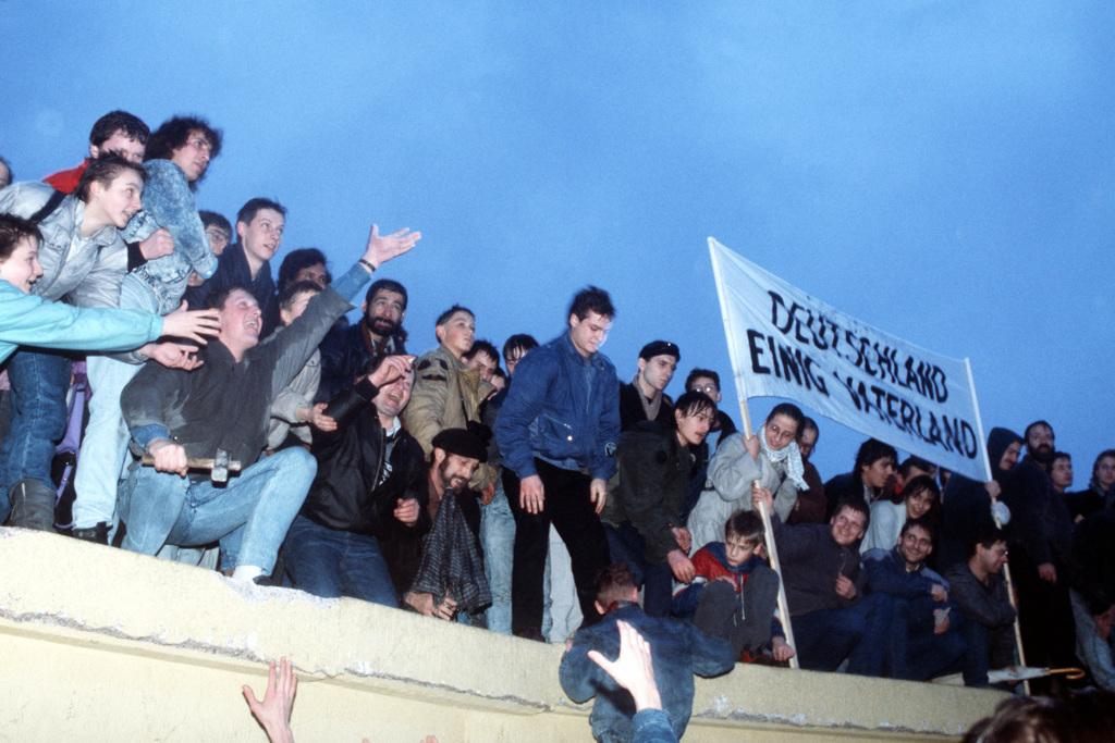 Crowds celebrate atop the Berlin Wall near the Brandenburg Gate in 1989
